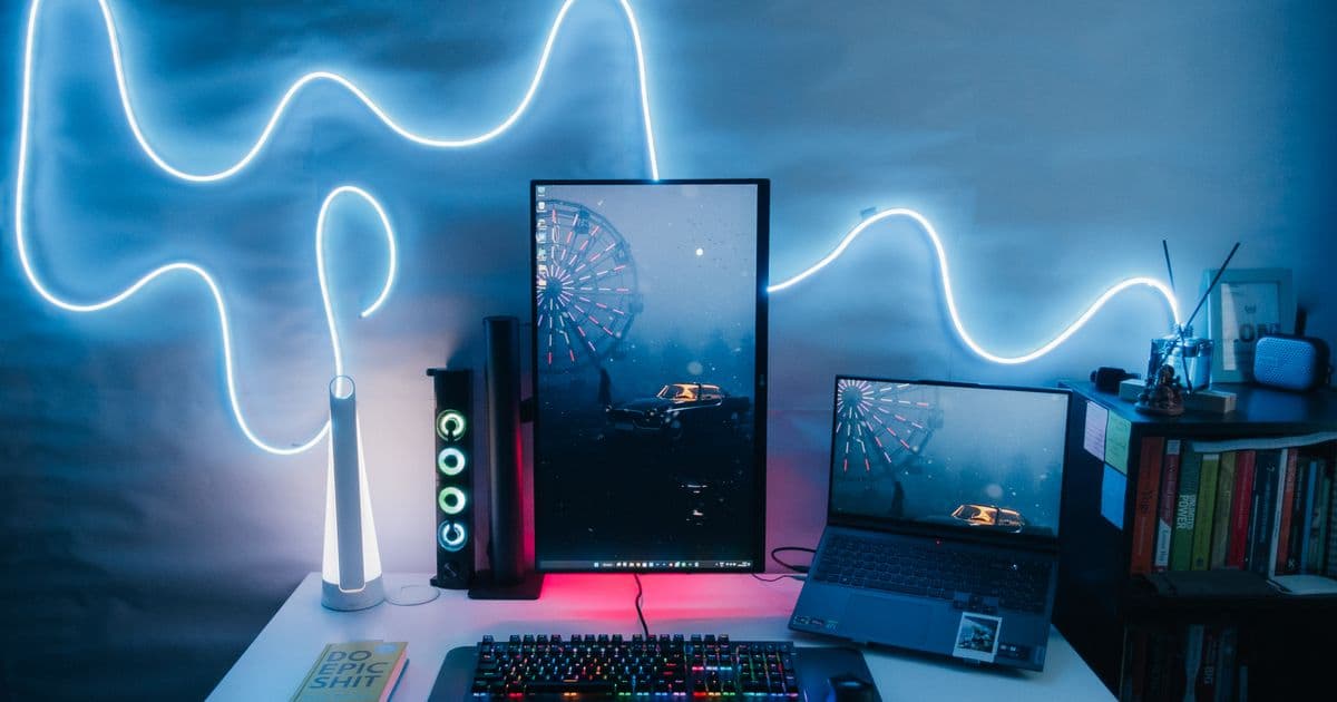 A modern desk setup with a vertical monitor and neon lighting