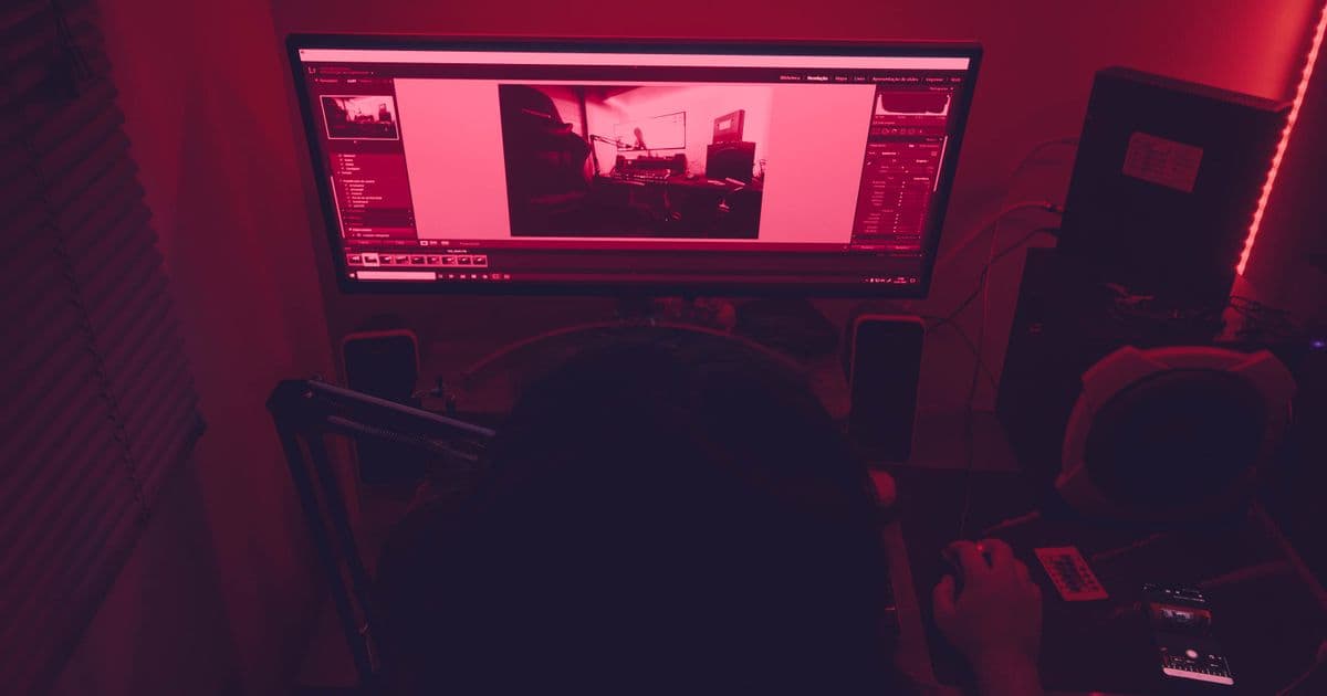 A desk with a monitor and gaming PC under red lighting