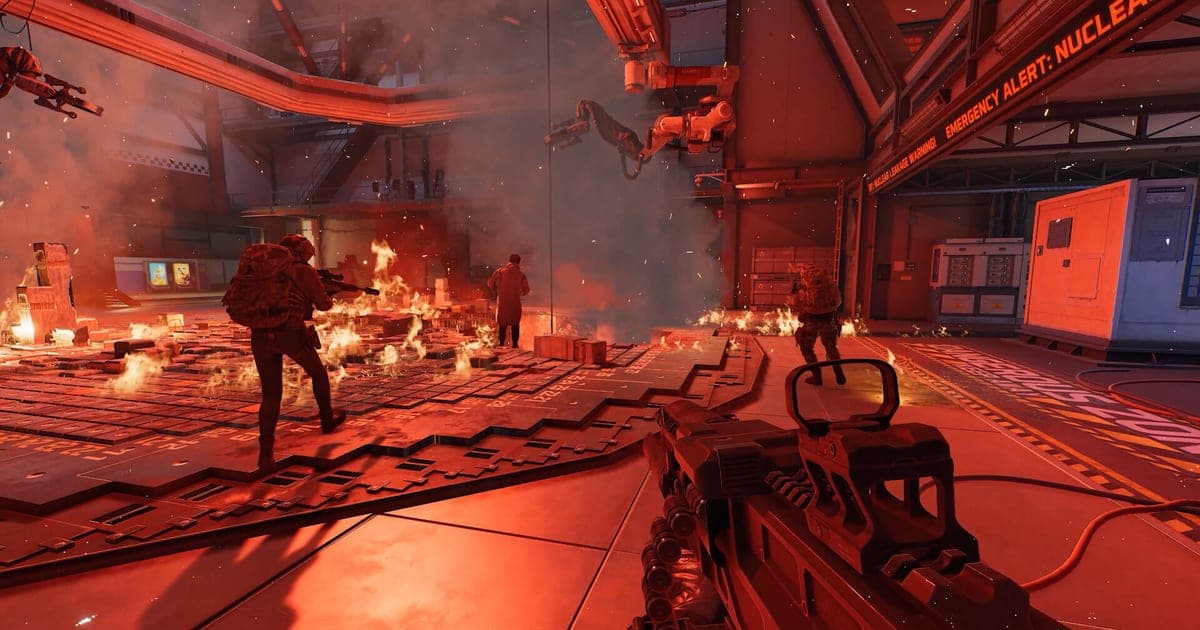 Actual Delta Force gameplay — a first-person firefight holding a rifle inside a facility lit by red alarm lights as flames spread