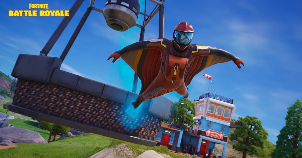 Actual Fortnite gameplay — a character in a wingsuit gliding off a crane gondola toward a fishing shack