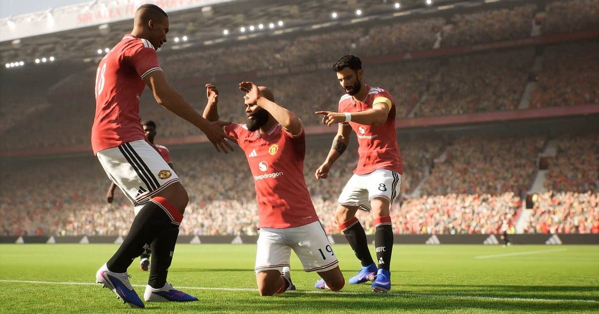 Players in red kits celebrate a goal together on the pitch, one sliding on his knees, in an eFootball match