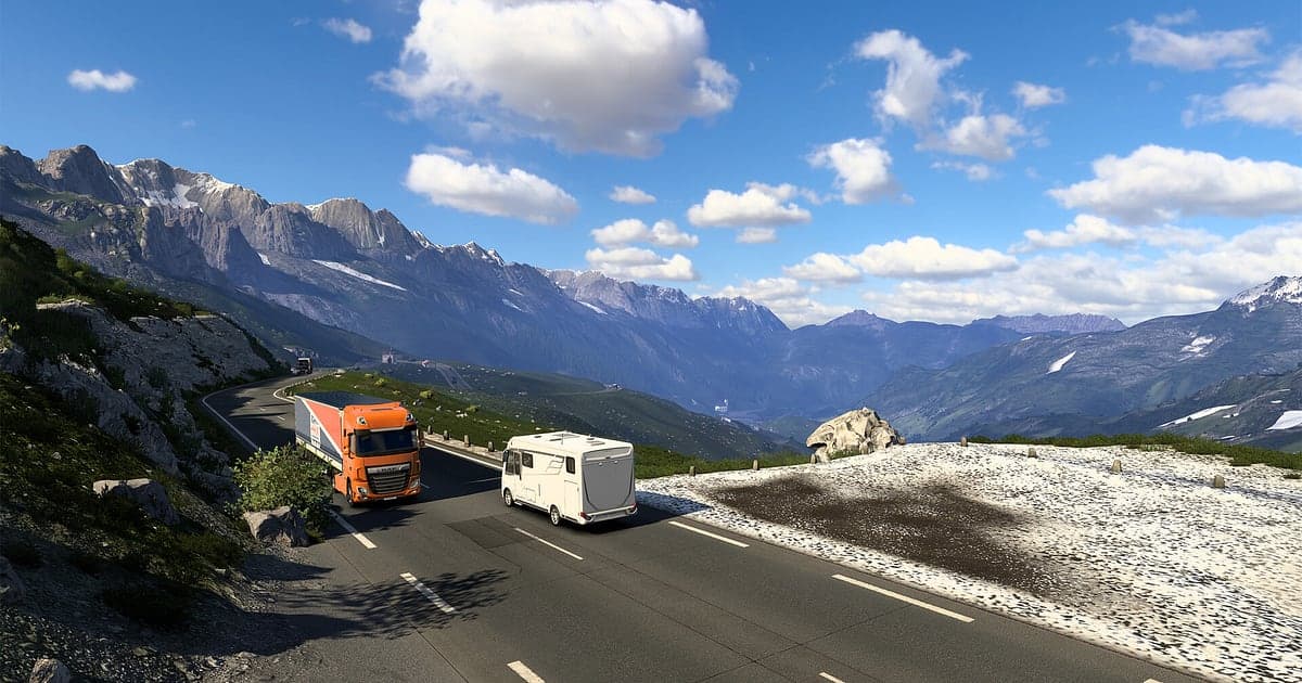 Ein orangefarbener Lkw und ein Wohnmobil fahren in Euro Truck Simulator 2 eine Bergstraße hinauf, dahinter verschneite Alpengipfel