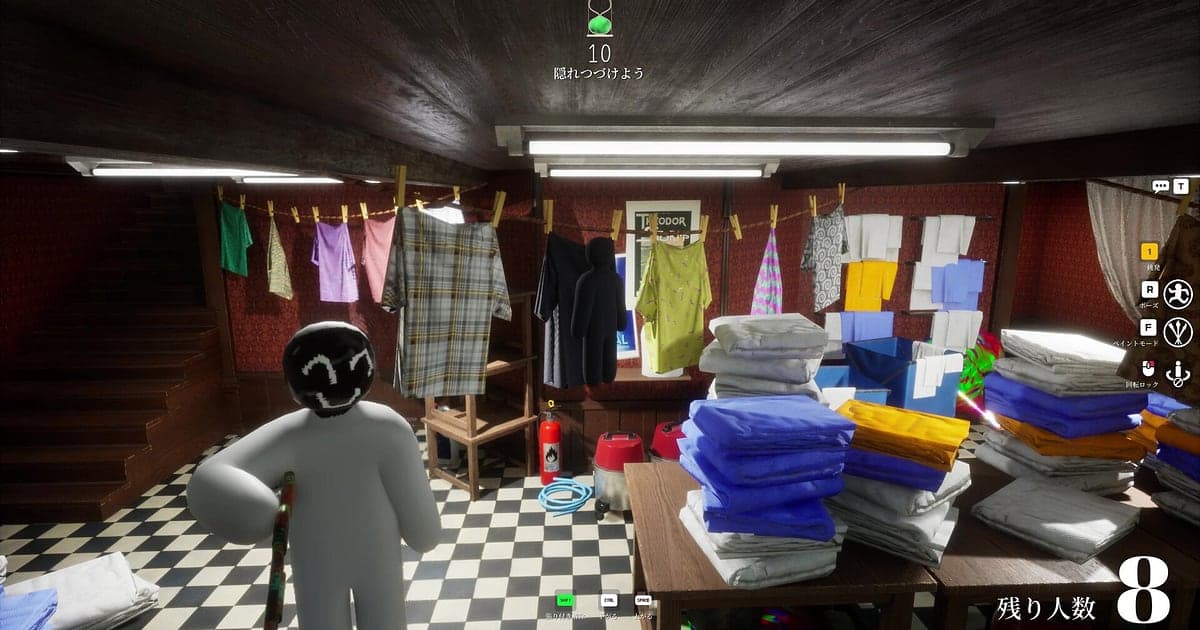 Lavandería en un sótano de MECCHA CHAMELEON donde un escondido blanco con una carita feliz pintada está parado entre pilas de ropa doblada bajo un tendedero