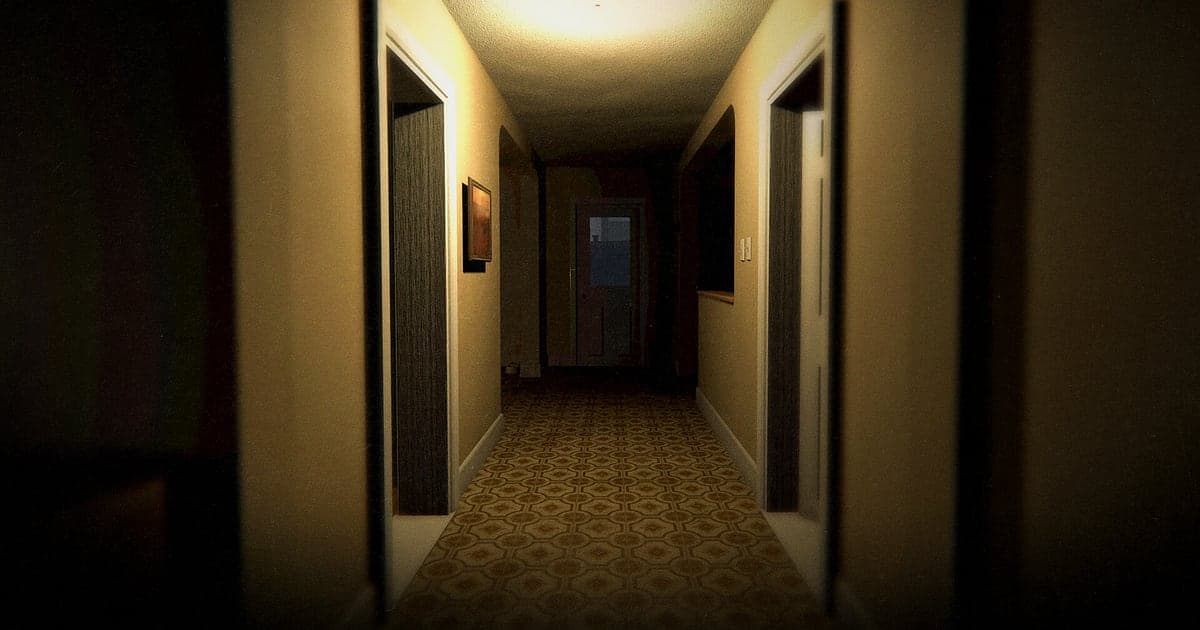 Hausinneres in Phasmophobia mit schmalem Flur, beleuchtet von einer einzigen Deckenlampe, links und rechts offene dunkle Türen und am Ende die Haustür