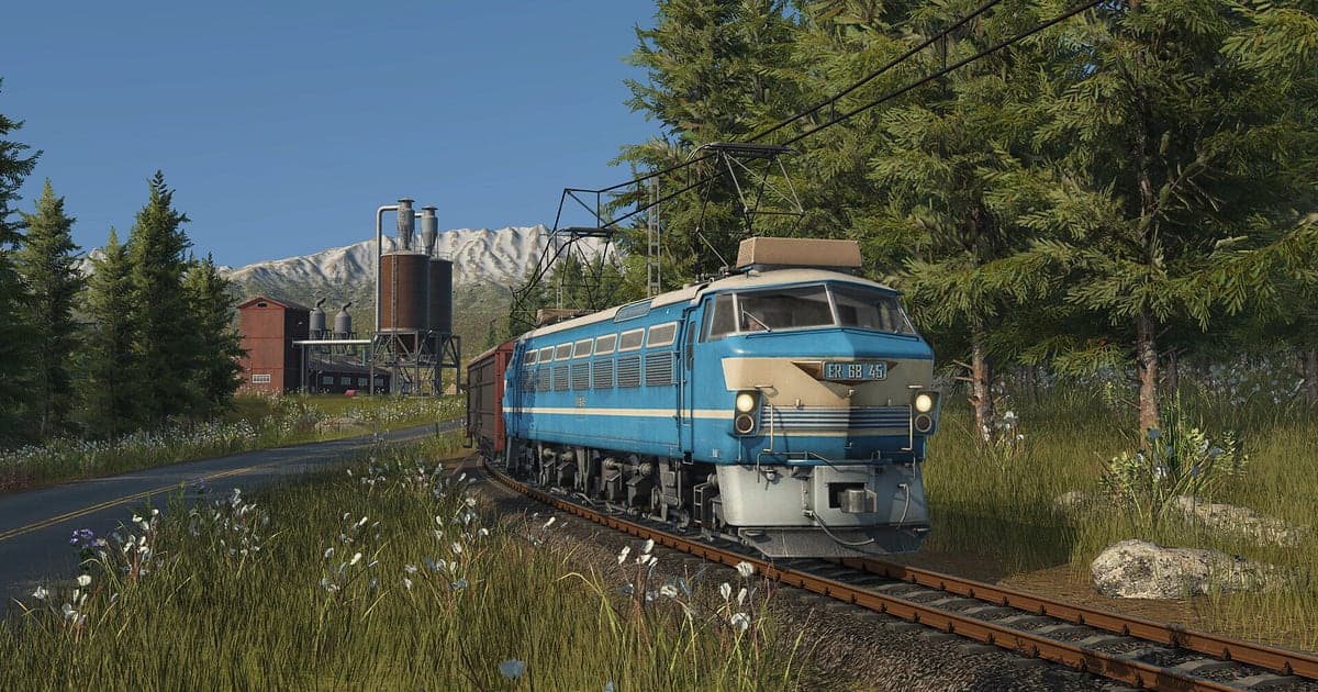 Eine blaue E-Lok zieht einen Güterzug über eine Waldstrecke, dahinter verschneite Berge, in Transport Fever 3
