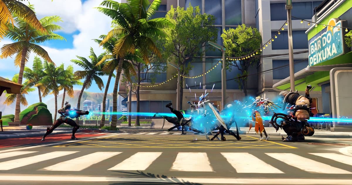 Hình ảnh Overwatch 2 chính thức của Blizzard — Sojourn bắn railgun dọc con phố rợp bóng cọ, tia sáng lao về phía kẻ địch