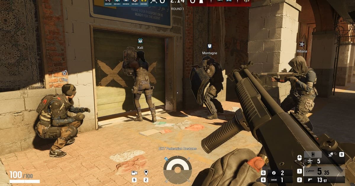 Cảnh chơi thật của Rainbow Six Siege — đồng đội dàn quân trước cánh cửa đã gia cố, tên các operator hiện rõ ở đầu vòng đấu