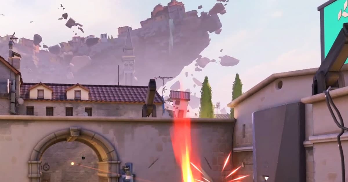 A first-person VALORANT gunfight with muzzle flash in front of an arched gate