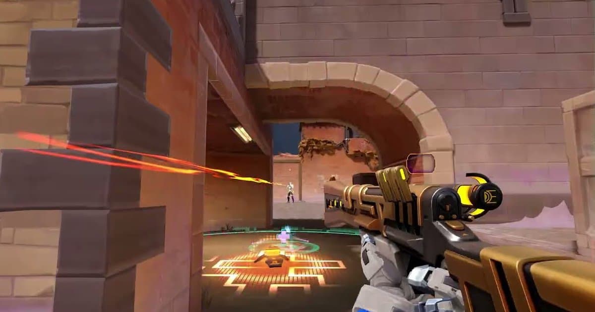 Troca de tiros em primeira pessoa do trailer oficial do modo Gauntlet: Glitched do VALORANT, com uma arma dourada e preta na mão, um traçante laranja chegando a um inimigo depois de um arco de tijolos e um padrão laranja brilhante no chão